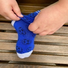 Child using their fingers and thumb to pull the sock over the ankle
