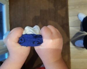 Child with their thumbs inside their sock