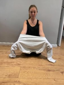 Girl lifting the jumper up off the floor keeping both hands inside of the jumper