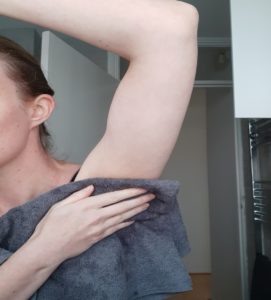Person drying their armpit with a towel