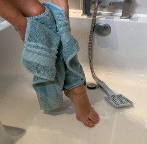 Person patting their leg dry with a towel