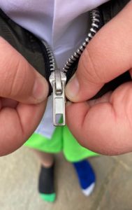 Person pushing the pin down into the zipper and into the box