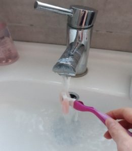 Person rinsing a razor under running warm water