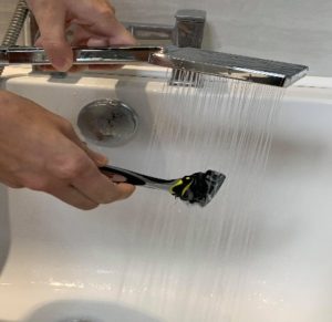 Person rinsing the razor under warm water