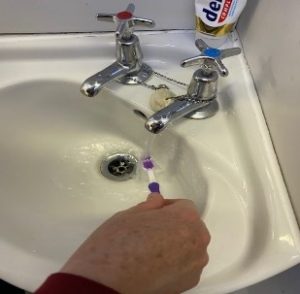 Person rinsing their toothbrush