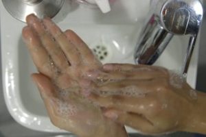 Person rubbing the tips of their fingers on the palm of their other hand