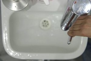 Person turning on a tap and wetting their hands with water