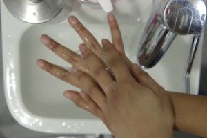 Person using one hand to rub the back of their other hand and in between their fingers