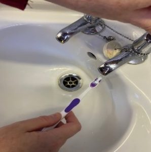 Person wetting the toothbrush under a running tap