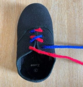 Picture shows a child's shoe with the red lace crossed over beside the blue lace