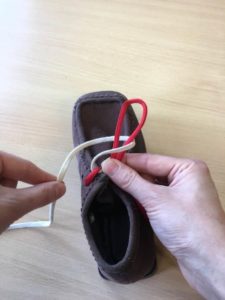 Picture shows someone placing the white lace down at the left side of the shoe