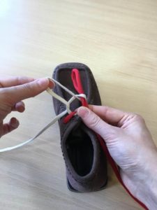 Picture shows someone pulling the new white loop (bunny ear) through the hole until it's the same size as the red loop (bunny ear)