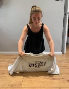 Girl sitting on the floor placing a jumper on the floor front side down