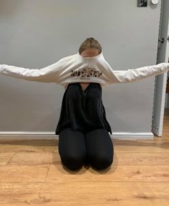 Girl straightening her arms out to pull the jumper over her head