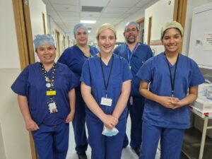 Work experience student with four operating department practitioners stood in the corridor in blue scrubs.